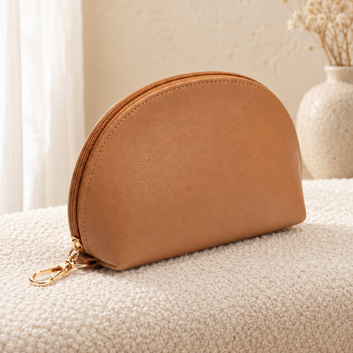 Tan half-moon cosmetic pouch in a cozy cream setting